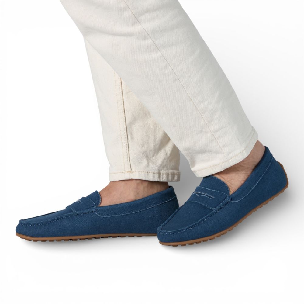 Blue Madrid Denim Drive Moccasins worn with white pants on a light gray background