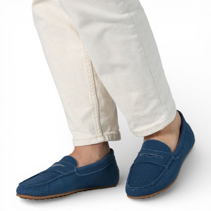 Blue Madrid Denim Drive Moccasins worn with white pants on a white background