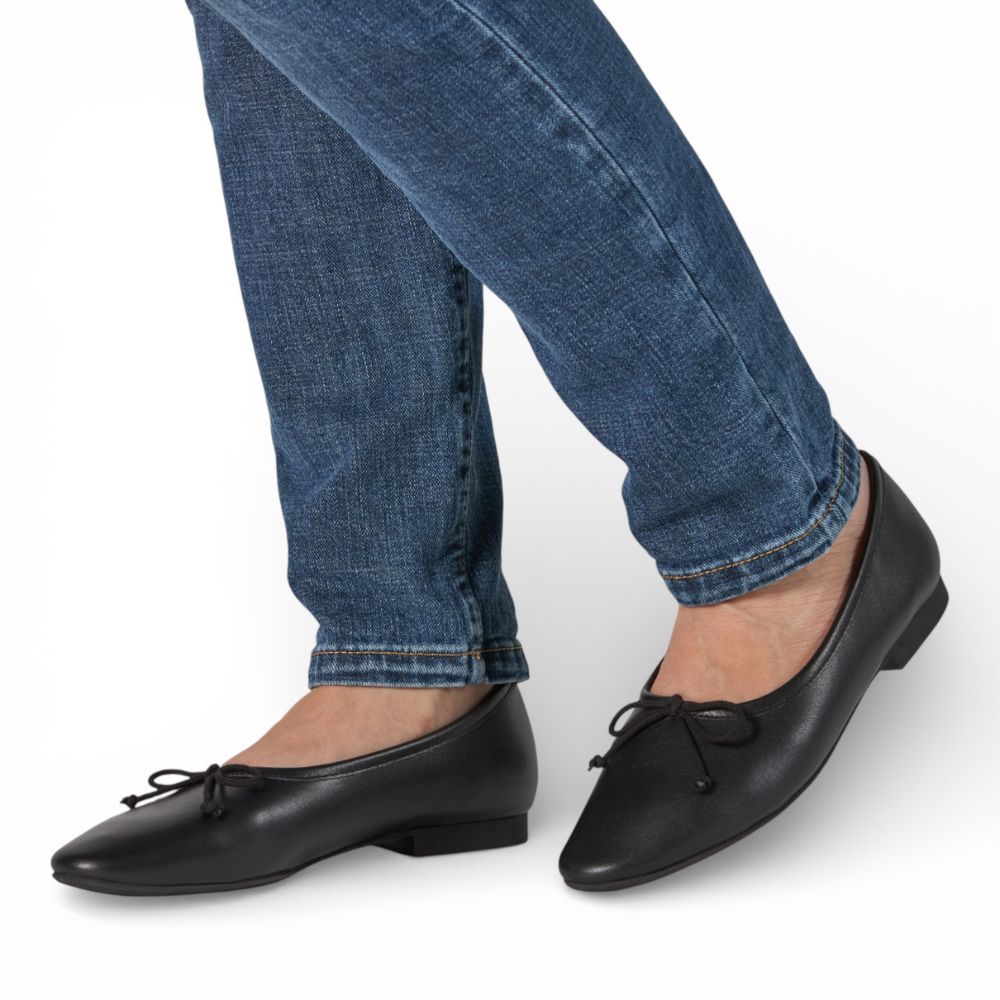 Roma Black Leather Elegant Flat worn with blue jeans on a white background
