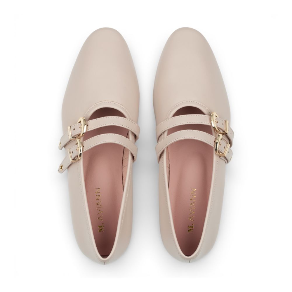 Pair of beige shoes with gold buckles on a white background
