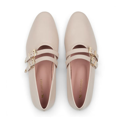 Pair of beige shoes with gold buckles on a white background